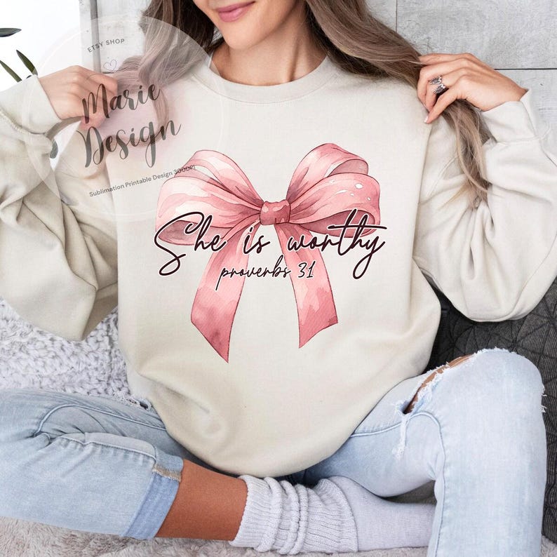 May include: A white sweatshirt with a pink bow and the text "She is worthy Proverbs 31" printed on it.