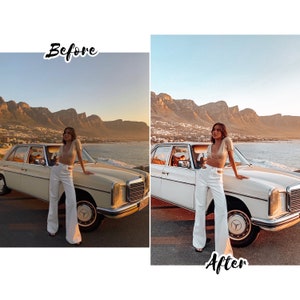 May include: A woman in a white outfit stands next to a vintage white car with a mountain range in the background. The sky is a light blue with a golden sunset.