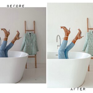 May include: A white bathtub with a person's legs and feet sticking out of it. The person is wearing light blue jeans and white heeled sandals. A green blazer is hanging on a wooden ladder behind the bathtub.