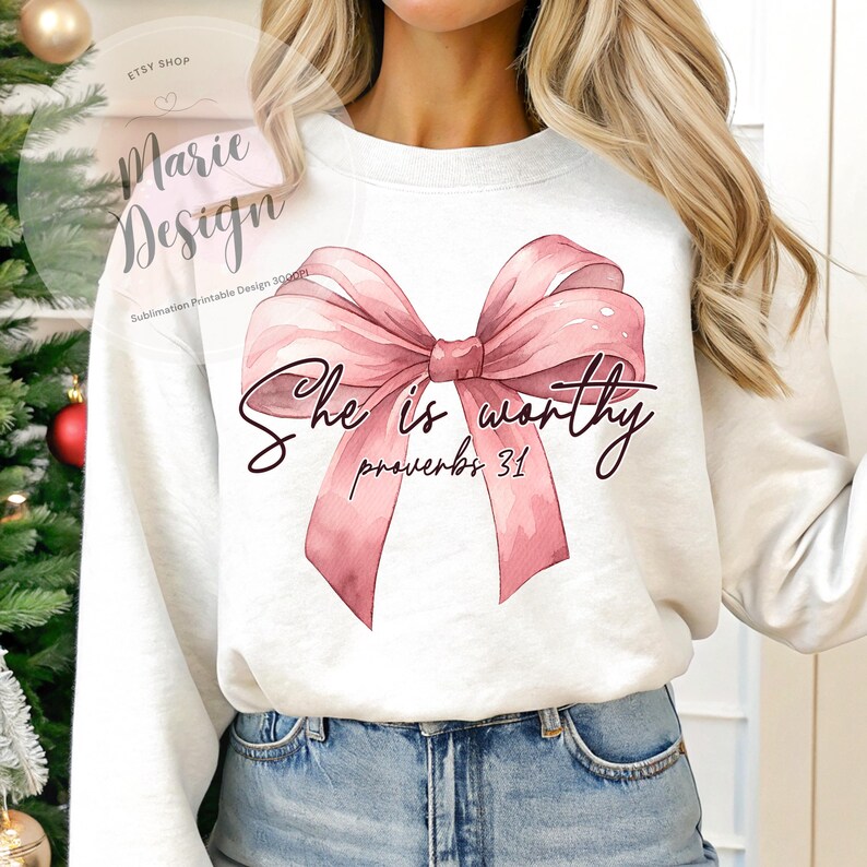 May include: A white sweatshirt with a pink watercolor bow and the text "She is worthy Proverbs 31" printed on the front.