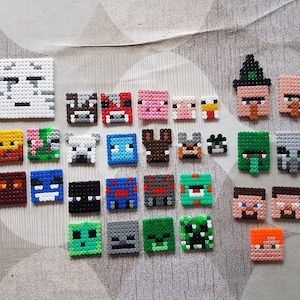 Könnte beinhalten: Eine Sammlung von 28 bunten Pixel-Art-Charakteren aus dem beliebten Videospiel Minecraft. Die Figuren bestehen aus kleinen Plastikperlen und sind in Reihen auf einer hellgrauen Oberfläche angeordnet.