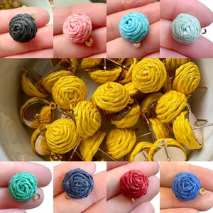 Könnte beinhalten: Sortiment handgefertigter Papier-Rosetten-Ohrringe in verschiedenen Farben, darunter Schwarz, Rosa, Blau, Gelb, Grün, Rot und Dunkelblau. Die Ohrringe sind an goldfarbenen Ohrsteckern befestigt.