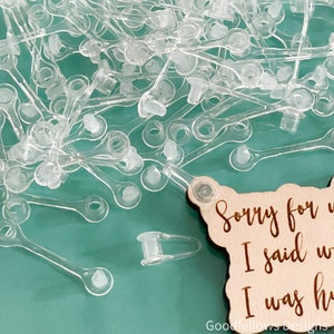 May include: A pile of clear plastic mask extenders with a wooden sign that reads "Sorry for what I said when I was hungry".