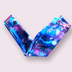Puede incluir: Un par de leggings con estampado de galaxia en tonos azules, morados y negros.