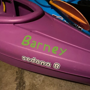 May include: Purple kayak with a green "Barney" sticker and a white "sedona 8" sticker.