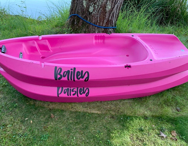 May include: A pink plastic kayak with the names "Bailey" and "Paisley" written on the side.