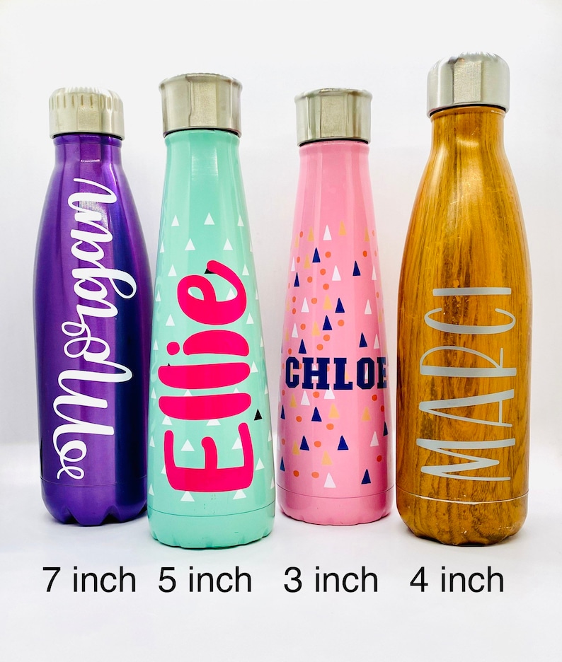 K&ouml;nnte beinhalten: Vier Edelstahl-Wasserflaschen mit verschiedenen Farben und Designs. Die Flaschen sind mit den Namen "Ellie", "Chloe", "Marci" und "Andie" beschriftet. Die Flaschen sind 17,8 cm, 12,7 cm, 7,6 cm und 10,2 cm hoch.