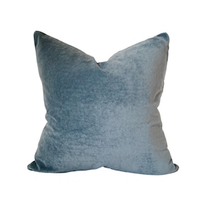 May include: A soft, blue velvet pillow with a square shape and a slightly textured surface.