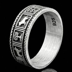 May include: A silver ring with an engraved design. The ring features a series of rectangular panels with various symbols, including a tree, a dog-like figure, and other abstract shapes. The ring is marked with "925" on the inside.