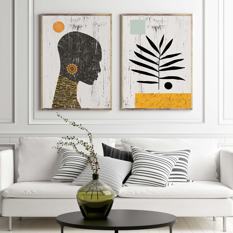 May include: Two abstract art prints with a white background. The print on the left features a black silhouette of a person's head with a yellow and orange patterned design. The print on the right features a black silhouette of a plant with a yellow and orange patterned design at the bottom.