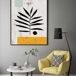 May include: A black and white abstract art print with a stylized leaf design and a yellow patterned stripe at the bottom. The print is framed and hanging on a gray wall.
