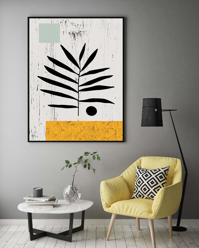 May include: A black and white abstract art print with a stylized leaf design and a yellow patterned stripe at the bottom. The print is framed and hanging on a gray wall.