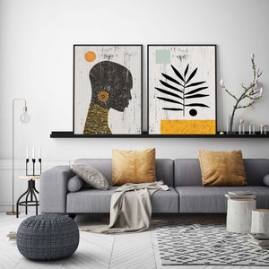 May include: Two black framed abstract art prints with a white background. The print on the left features a black silhouette of a person's head with a yellow circle and a yellow necklace. The print on the right features a black silhouette of a plant with a yellow rectangle and a blue rectangle.