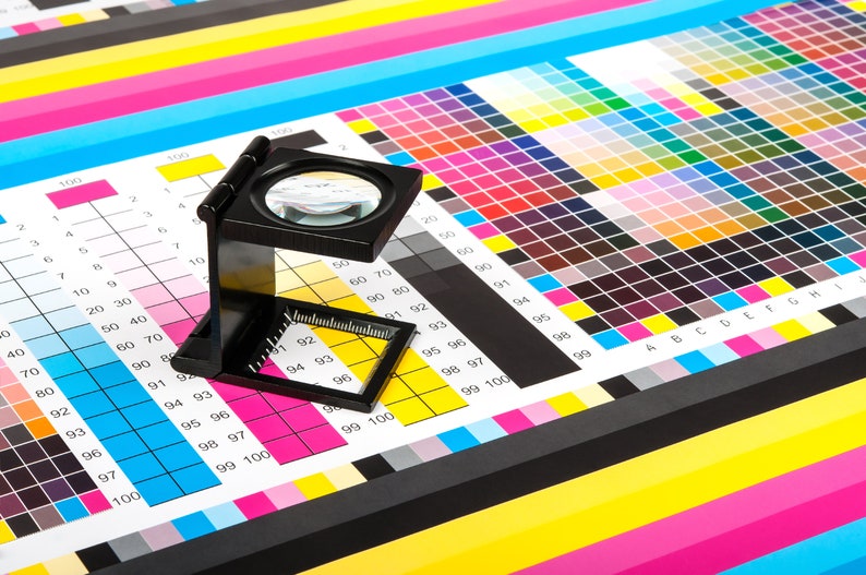Pu&ograve; includere: Una lente d'ingrandimento &egrave; posizionata su una cartella colori con quadrati numerati. La cartella viene utilizzata per abbinare i colori per la stampa.