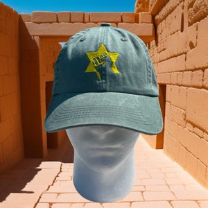 May include: A green baseball cap with a yellow embroidered Star of David and a raised fist inside the star.