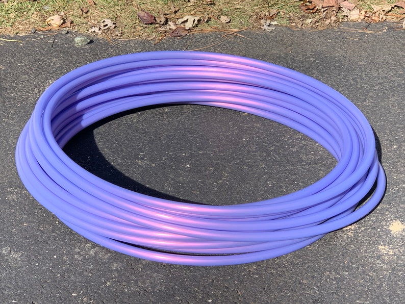 K&ouml;nnte beinhalten: Ein lila-rosa Reifen mit Metallic-Finish. Der Reifen ist auf einer grauen Oberfl&auml;che aufgerollt.