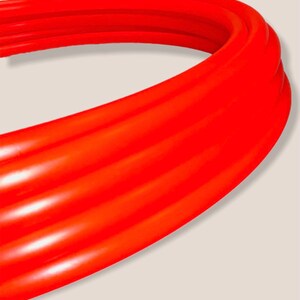 May include: Close-up of a bright orange, flexible, ribbed pipe. The pipe is curved and appears to be made of a durable material.