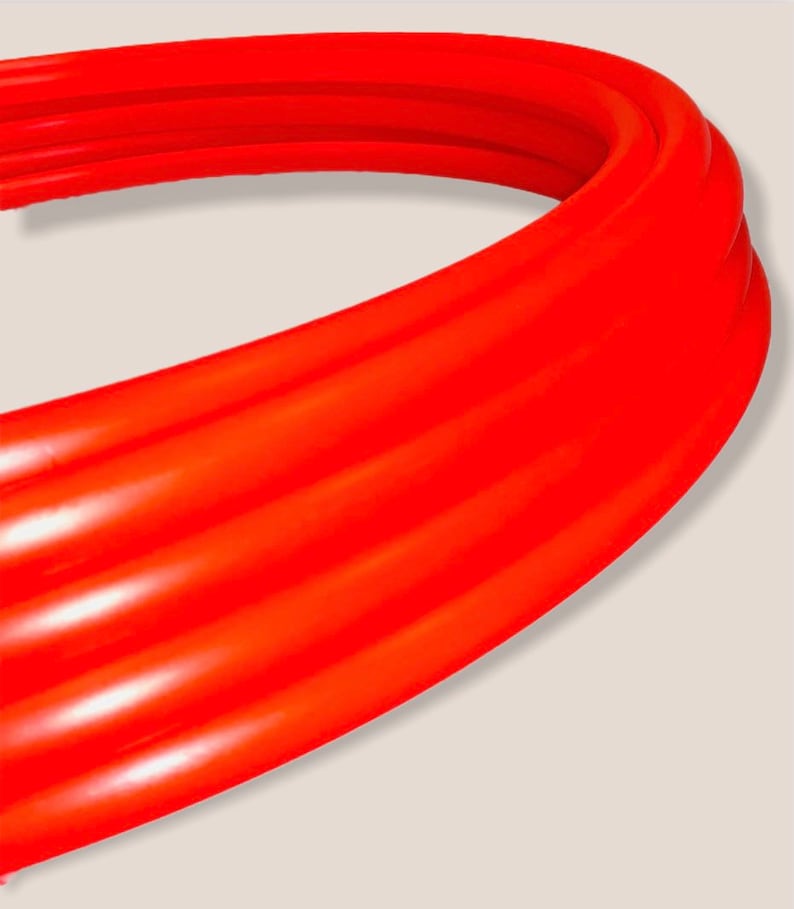 May include: Close-up of a bright orange, flexible, ribbed pipe. The pipe is curved and appears to be made of a durable material.