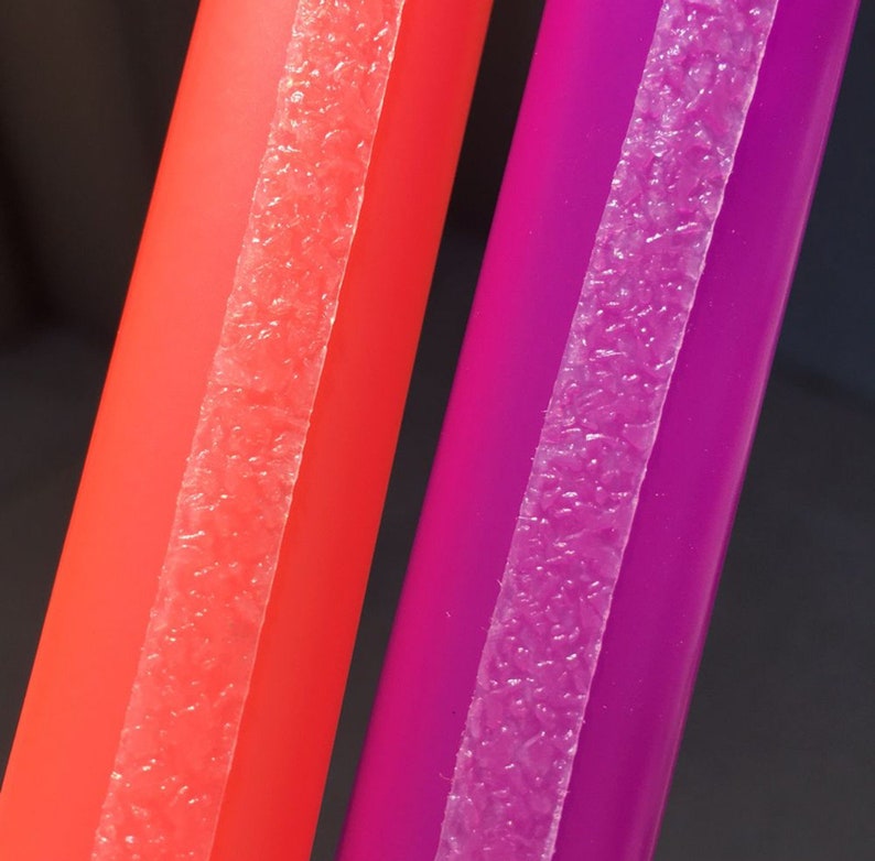May include: Close-up of two colorful straws. One is a vibrant red, and the other is a deep purple. Each straw has a textured, translucent strip running down its length. The background is a dark gray.