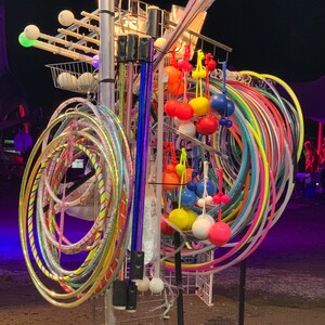 K&ouml;nnte beinhalten: Ein bunter Stand mit Reifen, B&auml;llen und St&ouml;cken aus Metall. Die Reifen sind in verschiedenen Farben und Gr&ouml;&szlig;en, die B&auml;lle sind rot, gelb, blau und wei&szlig;. Die St&ouml;cke sind lila, blau und wei&szlig;.