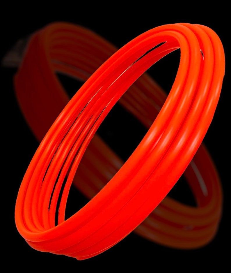 May include: Four orange plastic hula hoops stacked on top of each other. The hoops are all the same size and are made of a flexible plastic.