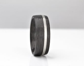 May include: A black carbon fiber ring with a silver inlay. The ring is smooth and has a polished finish.
