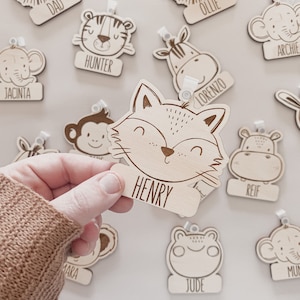 May include: Wooden name tags with animal illustrations and names, including Henry, Jacinta, Hunter, Archie, Lorenzo, Reif, Avery, Ollie, Dad, Kara, Jude, and Mum.