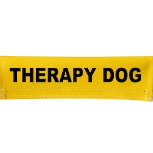 Peut inclure: Étiquette en tissu jaune avec le texte noir "THERAPY DOG".
