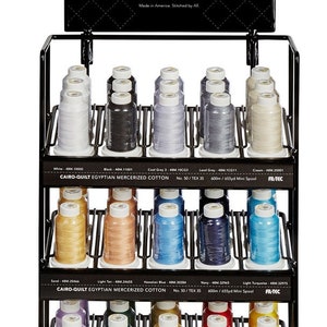 May include: A black metal display stand with three shelves holding spools of Cairo-Quilt Egyptian Mercerized Cotton thread. The spools are arranged in rows and are labeled with color names and numbers. The stand has a sign at the top that reads "Cairo-Quilt Egyptian Mercerized Cotton" and includes information about the thread, such as the size, length, and material.