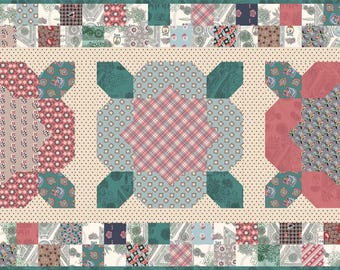 May include: A patchwork quilt table runner with a cream background and three floral designs in shades of red, pink, blue, and green. The floral designs are surrounded by a border of smaller patchwork squares.