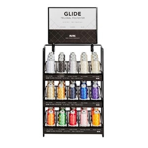 May include: A black metal display stand with three shelves holding spools of Glide Trilobal Polyester thread in various colours. The top shelf has a sign that reads "Glide Trilobal Polyester" and "Fil-Tec Made in America Stitched by All".