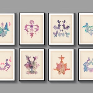 May include: Eight framed inkblot prints in a watercolor style. The prints are in various colors, including blue, green, purple, pink, and orange. The prints are all different shapes and sizes.