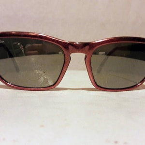 May include: A pair of burgundy cat-eye sunglasses with Ray-Ban written on the frame.