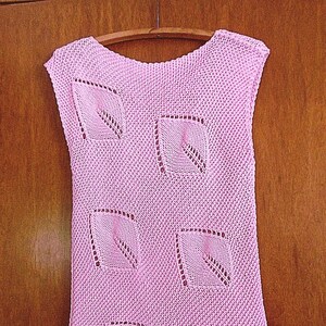 Puede incluir: Un top de punto rosa sin mangas con un patrón geométrico de hojas caladas.