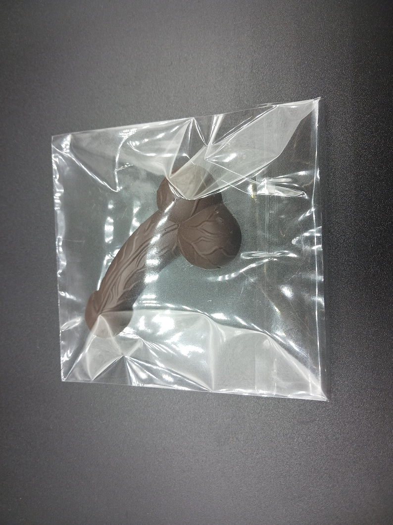 Op de afbeelding: Een donkerbruine chocolade replica van een mannelijk lichaamsdeel in een doorzichtige plastic zak.