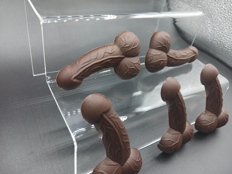Op de afbeelding: Vijf gegoten chocolade figuren in verschillende vormen en maten op een transparante acryl displaystandaard.