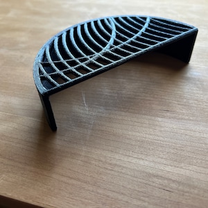 May include: A black, 3D printed, semi-circular shelf with a geometric design. The shelf is made of a sturdy, durable material and has a modern, minimalist aesthetic.
