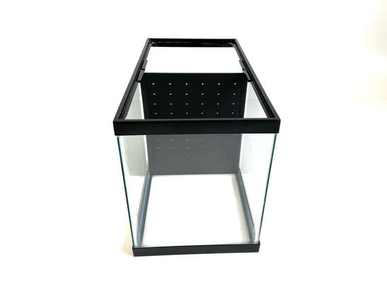 Peut inclure: Un aquarium en verre avec un cadre noir et un panneau en maille noire &agrave; l'int&eacute;rieur. L'aquarium est vide.
