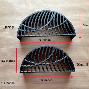 May include: Two black metal grill grates, one large and one small. The large grate is 6 inches wide and 3 inches tall. The small grate is 5 inches wide and 2.5 inches tall. Both grates are 1.4 inches high.