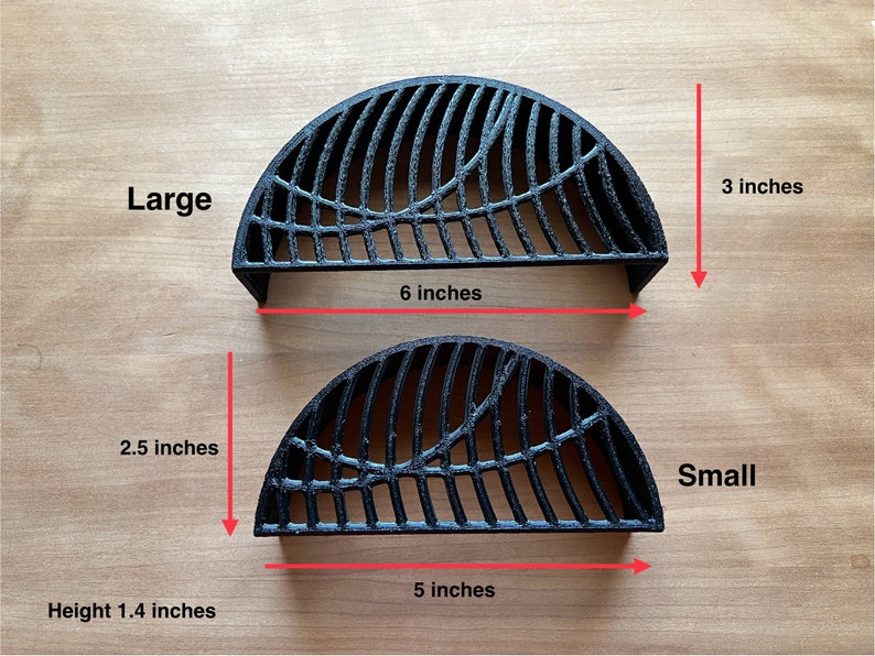 May include: Two black metal grill grates, one large and one small. The large grate is 6 inches wide and 3 inches tall. The small grate is 5 inches wide and 2.5 inches tall. Both grates are 1.4 inches high.