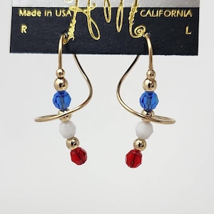 May include: Gold earrings with red, white, and blue beads. The earrings are made by Harry Mason, California.