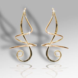 Può includere: Un paio di orecchini a cerchio in oro con un design delicato e a spirale. Gli orecchini sono realizzati in filo sottile e hanno un aspetto semplice ed elegante.