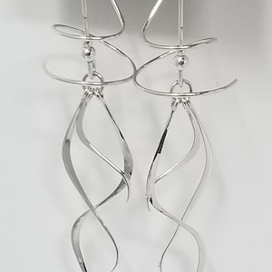 May include: Silver dangle earrings with a twisted wire design. The earrings are on a black card with the text "HARRY MASON DESIGNER JEWELRY CALIFORNIA".