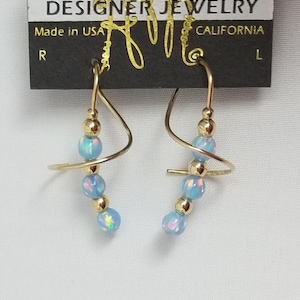May include: A pair of gold earrings with a spiral design and blue opal beads. The earrings are made by Harry Mason Designer Jewelry, California.
