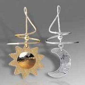 May include: A pair of gold and silver earrings featuring a sun and moon design. The earrings are made of wire and have a spiral design.