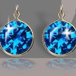 May include: A pair of blue crystal earrings with gold settings. The earrings are round and have a faceted design.