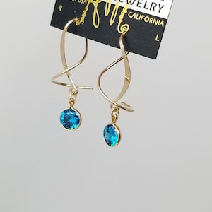 May include: Gold earrings with a twisted design and a blue gemstone dangle. The earrings are labeled "Mary Mason Designer Jewelry California".