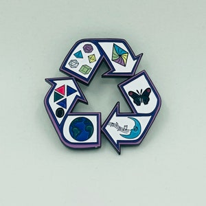 May include: A purple and blue enamel pin shaped like a recycling symbol. The symbol is divided into four sections, each with a different design. The top section features a colorful geometric design, the right section features a butterfly, the bottom section features a globe, and the left section features a crescent moon with musical notes.