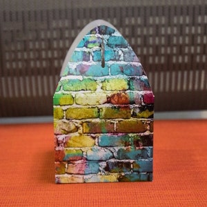 Puede incluir: Una peque&ntilde;a caja colorida con un dise&ntilde;o de patr&oacute;n de ladrillo. La caja est&aacute; hecha de cart&oacute;n y tiene una solapa en la parte superior.