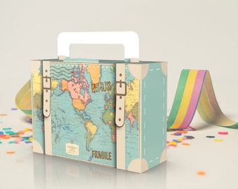 May include: A small, blue and white cardboard suitcase with a world map design. The suitcase has a handle and two straps with buckles. The text "FIRST CLASS" and "FRAGILE" is printed on the suitcase.